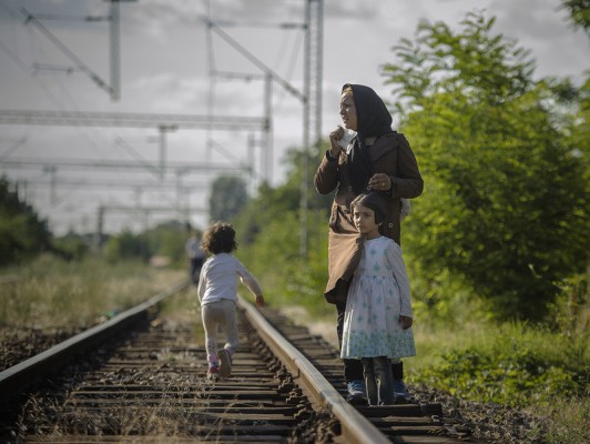 Një grua refugjate me fëmijët e saj qëndron në shinat e trenit. | Foto: Elena Geroska