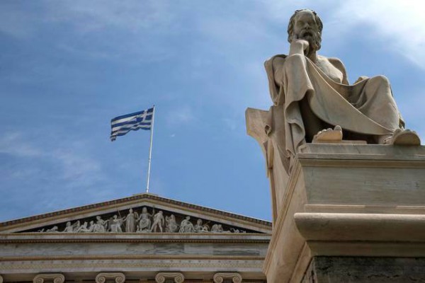 Statuja e mermertë e filozofit të lashtë grek Sokrati, qëndron përpara Akademisë së Athinës teksa një flamur grek valvitet, e premte 24 prill 2015. Ministri grek i financës u kritikua të premten nga kolegët e tij të eurozonës pasi dështoi në reformat ekonomike që duhen për të shmangur falimentin e shtetit. (AP Photo/Petros Giannakouris)