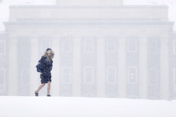 Një grua e re ecën në sfondin e kampusit të Universitetit Shtetëror të Pensilvanisë gjatë një stuhie dëbore, e premte 20 mars, 2015. (AP Photo/Matt Rourke)