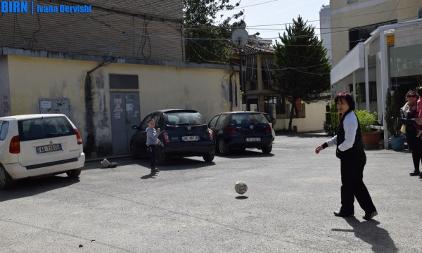 Një grua luan futboll me djalin në oborrin e asfaltuar përballë pallatit ku kanë parkuar makina. Tiranë, 22 mars 2016. Foto: Ivana Dervishi/BIRN.