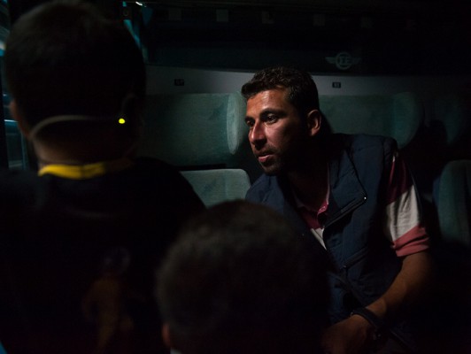 Alaa, një ish kapiten në ushtrinë e Sirisë, i flet fëmijëve të tij në trenin që po afrohet për në Tabanovcë | Foto: Tsvetomir Dimov