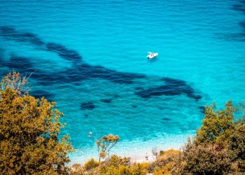 Beautiful turquoise water with a boat and greenery.