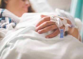 a woman laying in a hospital bed with an iv in her hand