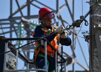 shallow focus photo of man fixing steel cable
