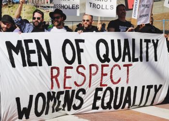 men holding white, black, and red Men of quality respect womens equality banner on road
