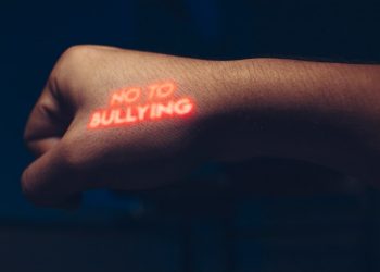 a person with a neon sticker on their arm saying no to bullying