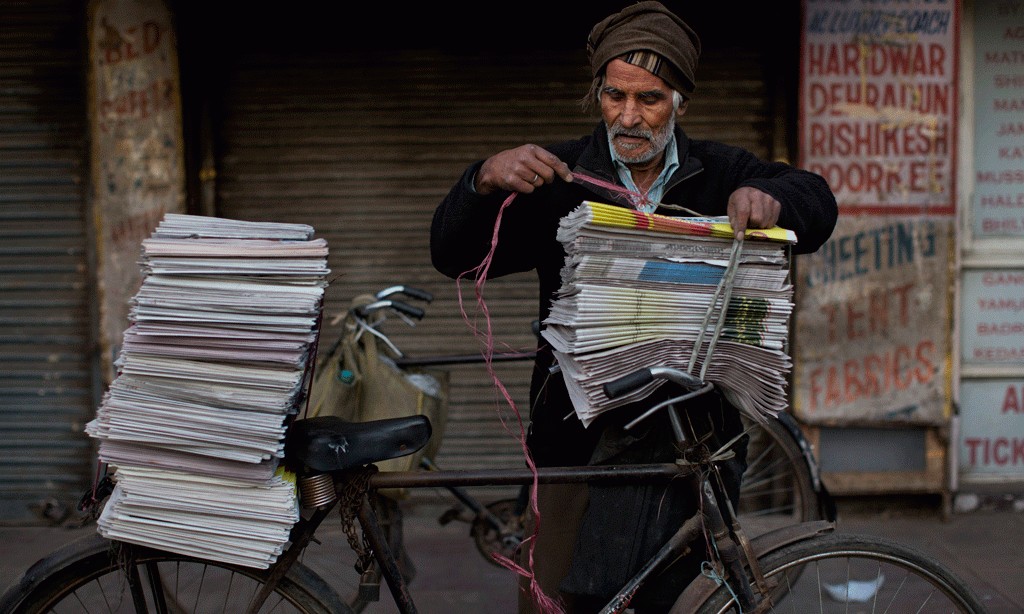 Një shitës ambulant gazetash në Nju Dehli në Indisë të premten më 27 shkurt 2015. Pjesa e vjetër të Delhit mbetet lagjja më e populluar dhe zemra simbolike e kryeqytetit të Indisë pavarësisht rrënimit të shumë ndërtesave. (AP Photo/Bernat Armangue)