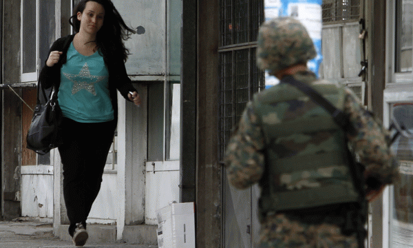 Një grua po vrapon për të dalë nga zona e operacionit policor në një lagje të banuar nga shqiptarët në Kumanovë më 9 maj 2015. Policia maqedonase thotë se është përleshur me një grup të armatosur të paidentifikuar ndërkohë që qeveria e Shkupit akuzohet se po sajon një luftë me shqiptarët për të shpëtuar nga zemërimi popullor ndaj skandaleve të qeverisë Gruevski. (AP Photo/Boris Grdanoski)