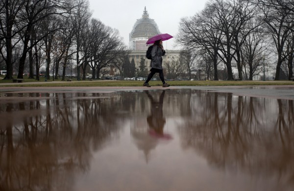 Një kalimtar ecën nëpër përzierjen e shiut dhe dëborës përgjatë një parku kombëtar në Uashington, e premte 20 mars, 2015. (AP Photo/Carolyn Kaster)