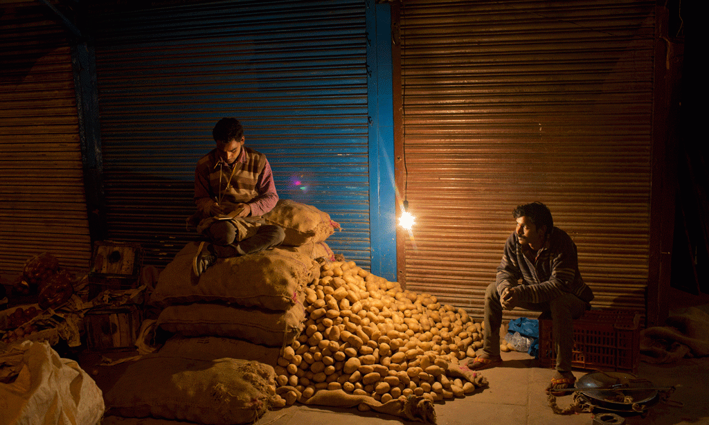 Tregtarë në Indi përgatiten herët në mëngjes për të nisur ditën e punës në tregun e shitjes me shumicë të zarzavateve në Nju Delhi më 27 shkurt 2015. (AP Photo/Bernat Armangue)