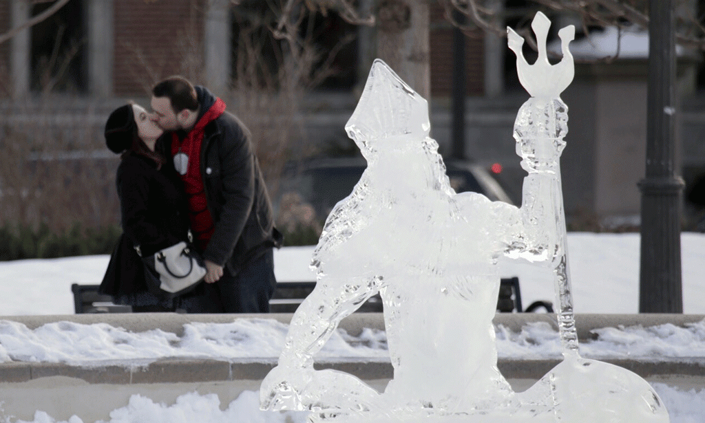 Jordan Gallo, majtas, puth Jordan DesJardins pranë një skulpture akulli në Filadelfia të Shteteve të Bashkuara më 26 shkurt 2015. (AP Photo/The Philadelphia Inquirer, Elizabeth Robertson)