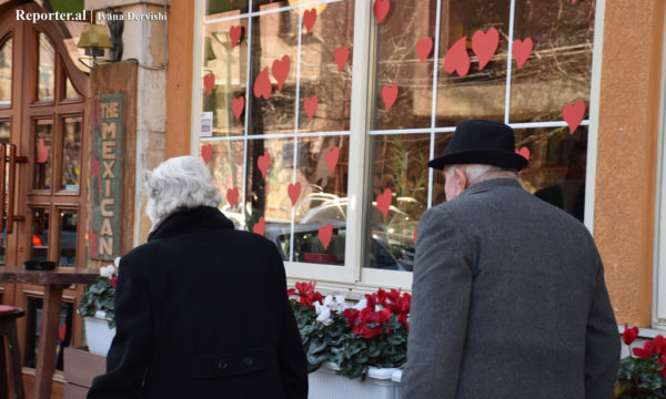 Një çift të moshuarish ecin krah një lokali të dekoruar për Ditën e Shën Valentinit.