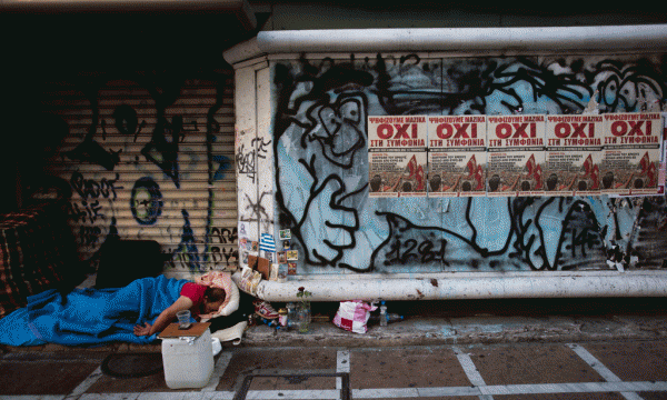 Një i pastrehë fle në hyrjen e një dyqani të mbyllur ku gjenden postera që lexojnë “Jo” në Athinën qendrore, 6 korrik 2015. (AP Photo/Emilio Morenatti)