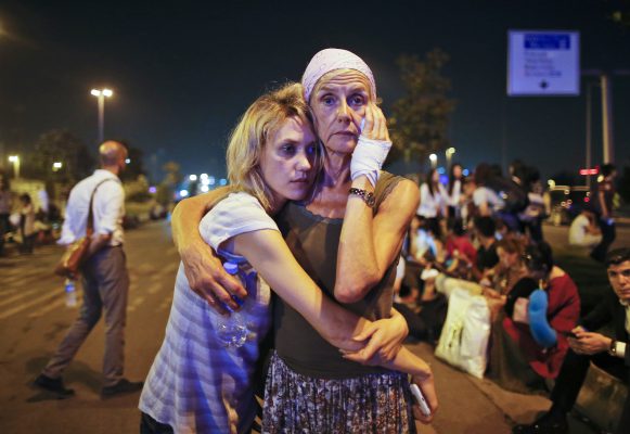 Pasagjerët përqafohen me njëri-tjetrin teksa presin jashtë aeroportit Ataturk në Stamboll. Foto: (AP Photo/Emrah Gurel) TURKEY OUT