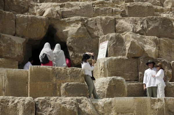 Tourists pose for pictures at the entrance of the Great Pyramid, built by Cheops, known locally as Khufu in Giza, Egypt, Thursday, June 2, 2016. A scientific team scanning the Great Pyramid aimed at discovering the famed pharaonic monument's secrets including possible hidden burial chambers. (AP Photo/Amr Nabil)