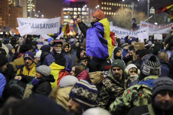 Turma njerëzish valvitin flamurin rumun jashtë godinës qeveritare. Foto: (AP Photo/Vadim Ghirda)