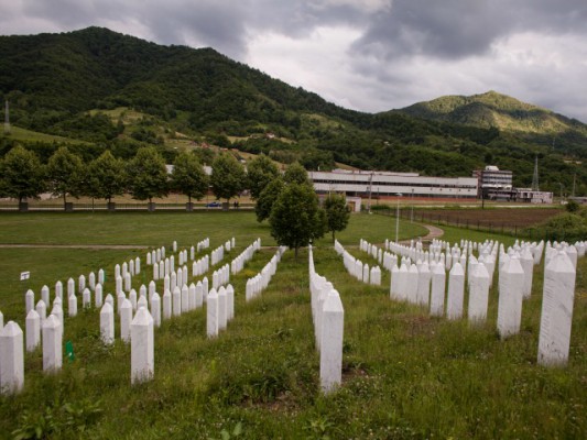 Varret e viktimave te Srebrenices me bazen e batalionit holandez te OKB ne sfond.Foto: Johannes De Bruycker. 