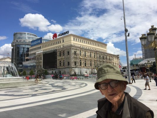Slavko Brezoski, 94, qëndron në sheshin kryesor të Shkupit, ku qendra tregtare moderniste të cilën ai e dizenjoi më 1956 u fsheh pas një fasade neoklasike. Foto: Nevena Brezoska