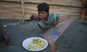 Një fëmijë po ushqehet me çfarë ka mbetur nga një festë popullore në Guahati, Indi, më 2 janar 2016. (AP Photo/Anupam Nath)