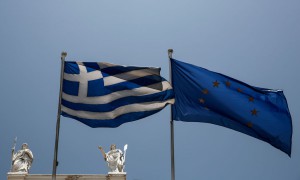 Një flamur grek dhe një i Bashkimit Europian po valëviten pranë statujave të Perëndeshës Athina, majtas dhe Nautilia, para muzeut Benaki në Athinë, Greqi më 17 korrik 2015. (AP Photo/Yorgos Karahalis)