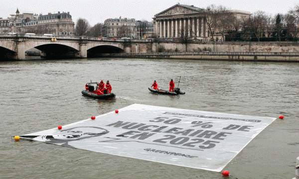 Aktivistët e Greenpeace po shpalosin një banderolë mbi lumin Senë pranë Asamblesë Kombëtare të Francës në Paris më 9 mars 2015. Aktivistët po protestojnë dhe kërkojnë që Franca të ulë pjesën e energjisë elektrike të siguruar nga energjia bërthamore. Banderola paraqet një premtim elektoral të presidentit Francois Hollande për uljen e varësisë së Francës nga energjia bërthamore. Franca siguron dy të tretat e elektricitetit të vet nga centralet bërthamore, gjë që i ka mundësuar këtij vendi të sigurojë energjinë elektrike më të lirë në Europën Perëndimore. Premtimi i qeverisë socialiste të Hollande është që kjo varësi të ulet në 50 për qind deri në vitin 2025. (AP Photo/Remy de la Mauviniere)