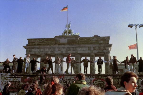 Muri i Berlinit Në këtë foto arkivë e 10 nëntorit 1989, berlinezët po këndojnë dhe kërcejnë mbi Murin e Berlinit pranë portës së Brandeburgut për të festuar ditën pas hapjes së kufirit mes Gjermanisë Lindore dhe Asaj Perëndimore. Gjermania lindore ndërtoi 155 kilometra mure si një “mur mbrojtës anti-fashist” me arsyetimin se do të mbronte qytetarët e vet nga Perëndimi por që në fakt kishte synimin për të ndaluar nënshtetasit e Gjermanisë Lindore nga emigrimi në perëndim. (AP Photo/Thomas Kienzle, File)