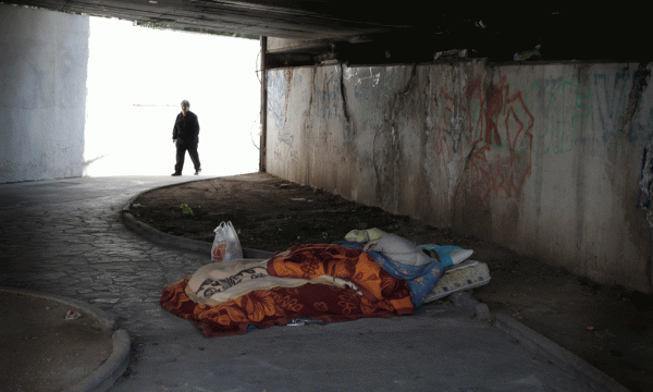 Një burrë i pastrehë po fle nën një urë në Athinë më 19 mars 2015. (AP Photo/Petros Giannakouris)