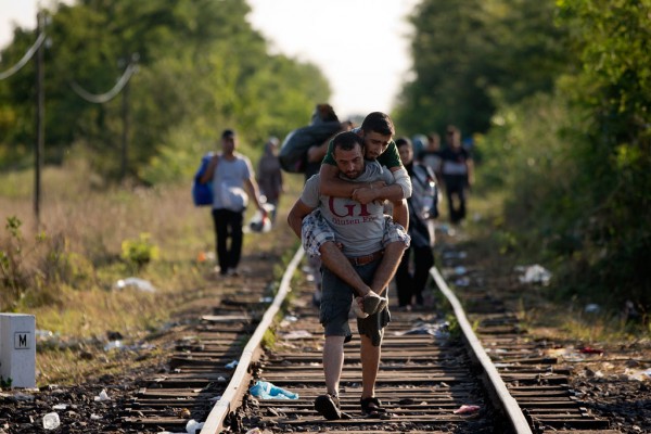 Emigrantët në Hungari Një refugjat po mban në krahë një tjetër përgjatë hekurudhës që lidh Serbinë me Hungarinë më 26 gusht 2015. Mbi 10 mijë refugjatë kanë mbërritur në Hungari përgjatë ditëve të fundit ndërkohë që Hungaria është duke ndërtuar gardhin e vet shumëmilionësh, i cili konsiderohet një investim i kotë pasi vështirë se mund të ndalojë ndokënd. (AP Photo/Darko Bandic)