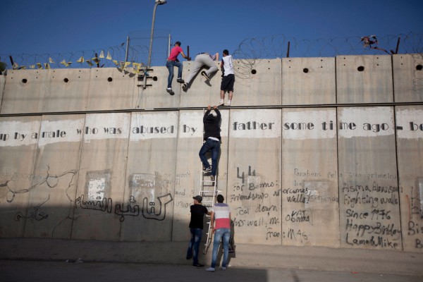 Muri i Palestinës Në këtë foto të 19 qershorit 2015, palestinezë të rinj po përdorin një shkallë për t’u ngjitur mbi murin ndarës me Izraelin në Al-Ram, Jeruzalem. Izraeli ka ndërtuar shumë mure dhe gardhe, përfshirë barrierën ndarëse të Bregut Perëndimor e cila pritet të jetë 700 kilometra e gjatë kur të përfundohet. Izraeli pretendon se muri synon ta mbrojë atë nga sulmuesit palestinezë ndërsa palestinezët thonë se ai mur përbën një grabitje toke që synon të ndalojë ndërtimin e një shteti të pavarur palestinez. (AP Photo/Majdi Mohammed, File)