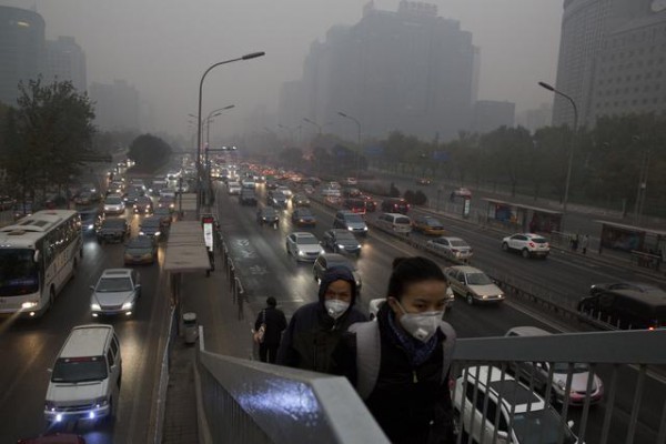 Këmbësorët po ecin duke mbajtur një maskë kundër ndotjes ndërsa po kapërcejnë një autostradë me nivel të lartë trafiku në Pekin të Kinës më 29 nëntor 2014. Kina po përjeton prej tri dekadash rritje të paprecedent ekonomike, por kjo gjë ka sjellë njëkohësisht rritje të frikshme të nivelit të ndotjes. (AP Photo/Ng Han Guan)