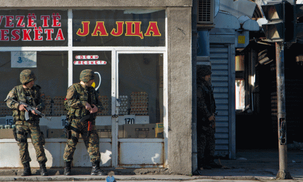 Policë të forcave speciale të Maqedonisë po mbrohen mëngjesin e së dielës në Kumanovë ku luftimet kanë rifilluar për ditën e dytë në një fushëbetejë ku Maqedonia po përplaset me një grup të armatosur dhe të paidentifikuar ndërkohë qe deklaratat e autoriteteve janë kontradiktore. 10 maj 2015. (AP Photo/Visar Kryeziu)