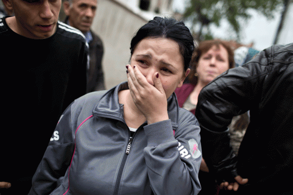 Një grua po qan ndërsa shikon dëmet në shtëpinë e saj të shkatërruar nga luftimet në lagjen e shqiptarëve në Kumanovë më 11 maj 2015. (AP Photo/Marko Drobnjakovic)