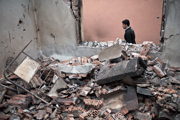 Një burrë kalon pranë një shtëpie të shkatërruar nga luftimet në Kumanovë më 11 maj 2015. (AP Photo/Marko Drobnjakovic)