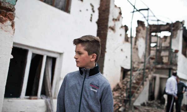 Një i ri po ecën pranë shtëpive të shkatërruara në Kumanovë më 11 maj 2015. (AP Photo/Marko Drobnjakovic)