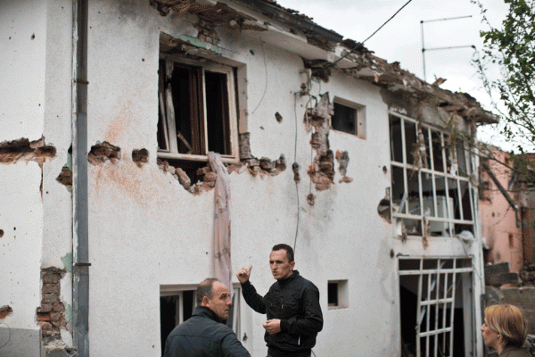 Një burrë ecën pranë një shtëpie të shkatërruar nga luftimet në Kumanovë më 11 maj 2015. (AP Photo/Marko Drobnjakovic)