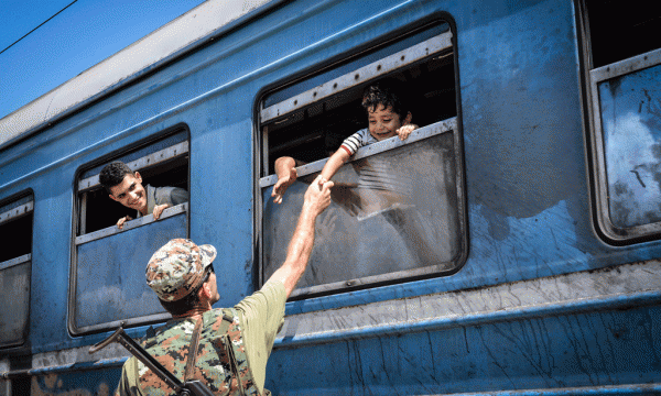 Nje polic maqedonas pershendet refugjatet ne tren. 25 gusht 2015. Foto nga Elvin Shulku