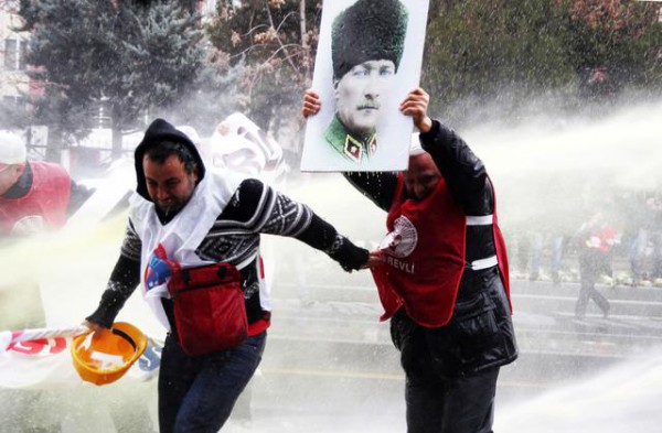 Një protestues përdor posterin e themeluesit të Turqisë moderne për t'u mbrojtur nga policia gjatë një tubimi. (AP Photo) 