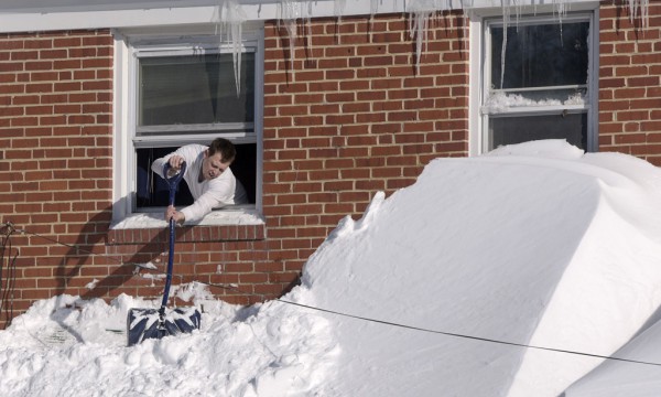 Shawn Covelly po shtyn dëborën nga dritarja e tij më 24 janar 2015 në Touson Meriland. (AP Photo/Steve Ruark)