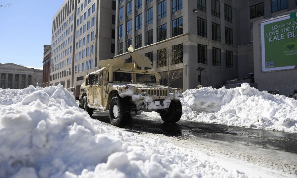 Një automjet ushtarak Humvee po ecën përgjatë rrugëve të Uashingtonit ndërsa në të dy anët e rrugës janë bërë pirgje të mëdha me dëborë më 24 janar 2014. Miliona amerikanë filluan të nxjerrin makinat e mbuluara nga dëbora të dielën pasi stuhia e stërmadhe e shoqëruar me erë me forcën e uraganeve hodhi një sasi rekord dëbore në pjesën më të madhe të Bregut Lindor të SHBA-së. (AP Photo/Nick Wass)