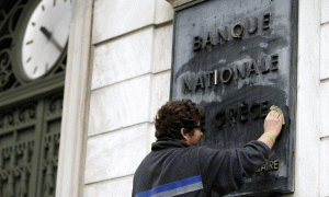 Një punëtor po pastron një tabelë mermeri ku shkruhet në frëngjisht “Banka Kombëtare e Greqisë” në Athinë më 9 shkurt 2015. Qeveria e re e Greqisë e futi veten në rrugën e përplasjes me Gjermaninë, një betejë që ka gjasa ta humbë. (AP Photo/Thanassis Stavrakis)