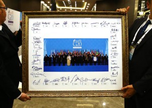 Dy persona mbajnë një foto grupi të liderëve të G-20, të nënshkruar prej tyre në samitin e mbajtur në Antalia, Turqi. 16 nëntor 2015. Foto nga (Anadolu Agency via AP, Pool)
