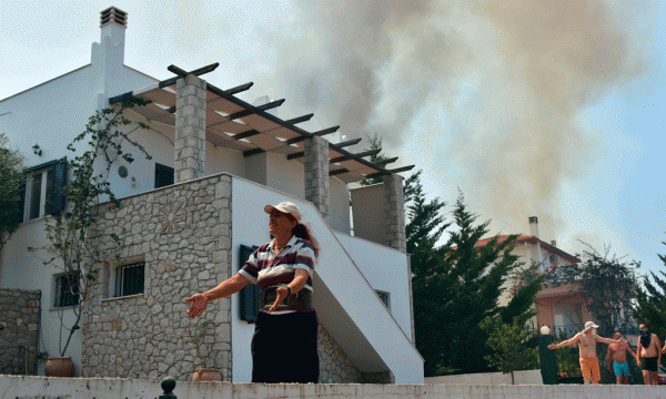 Një grua reagon ndërsa zjarri i afrohet një shtëpie në fshatin turistik Asini pranë qytezës Nafplio, 140 kilometra në jugperëndim të Athinës më 20 korrik 2015. (AP Photo/Vangelis Bougiotis)