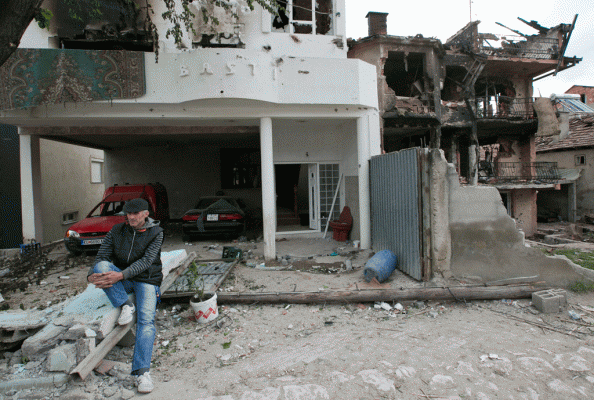 Një banor është ulur para shtëpisë së tij të shkatërruar në lagjen e Kumanovës ku në fundjavë pati luftime mes një grupi shqiptarësh dhe forcave maqedonase mëngjesin e 11 majit 2015. (AP Photo/Visar Kryeziu)