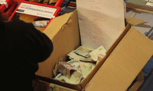 Një llogaritare në një shtëpi botuese mban paratë nga shitja e librave dhe numrin e tyre. Foto: Ivana Dervishi/BIRN.