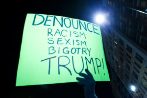 Një protestues po mban një pankartë gjatë një marshimi në Uashington kundër Presidentit të Zgjedhur Donald Trump më 12 nëntor 2016. Dhjetëramijëra njerëz marshuan nëpër rrugët e Shteteve të Bashkuara në protesta që vijojnë prej pesë ditësh. (AP Photo/Jose Luis Magana)