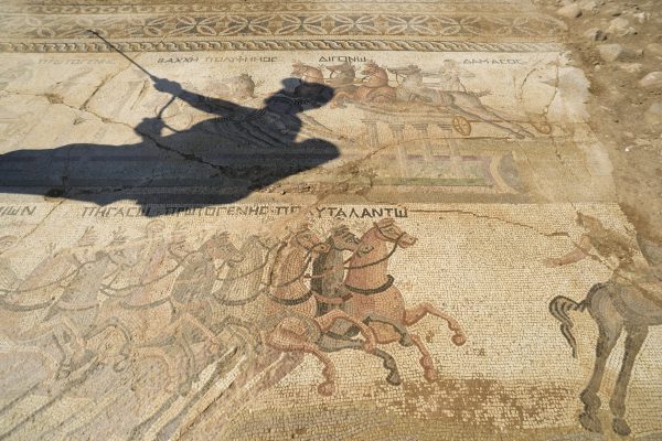 An archeologist in a shadow, sprays water on a rare mosaic floor dating to the 4th century depicting scenes from a chariot race in the hippodrome, in Akaki village outside from capital Nicosia, Cyprus, on Wednesday, Aug. 10, 2016. The 4th century mosaic rare is the only one of its kind in Cyprus and one of only handful in the world. (AP Photo/Pavlos Vrionides)