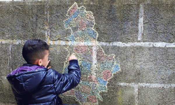 Një djalosh vizaton hartën e Shqipërisë me ndarjen e re territoriale në një mur. Foto: Ivana Dervishi/BIRN.