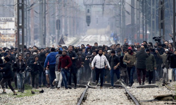 Në këtë foto të kapur nga ana maqedonase e kufirit, refugjatët dhe migrantët e bllokuar në anën greke po i afrohen kufirit ndërsa përpiqen të hyjnë në Maqedoni të hënën më 29 shkurt 2016. (AP Photo/Boris Grdanoski)