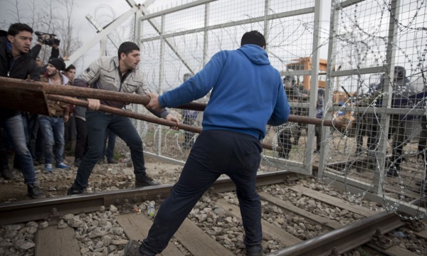 Refugjatë dhe migrantë po përpiqen të shkatërrojnë gardhin mes Greqisë dhe Maqedonisë nga ana greke e kufirit ndërsa policia maqedonase është në gadishmëri pranë fshatit Idomeni më 29 shkurt 2016. Nuk pati raportime për të plagosur. (AP Photo/Giannis Papanikos)