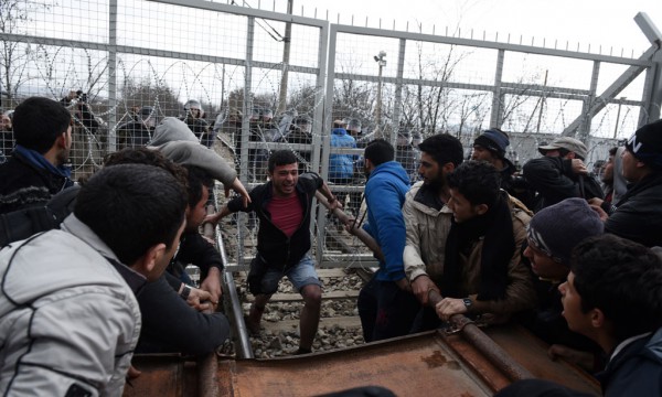 Refugjatët arrijnë të shkatërrojnë një pjesë të gardhit me tela me gjemba dhe po hedhin gurë ndaj policisë maqedonase nga ana greke e kufirit ndërsa maqedonasit iu përgjigjën duke hedhur gaz lotsjellës. (AP Photo/Boris Grdanoski)